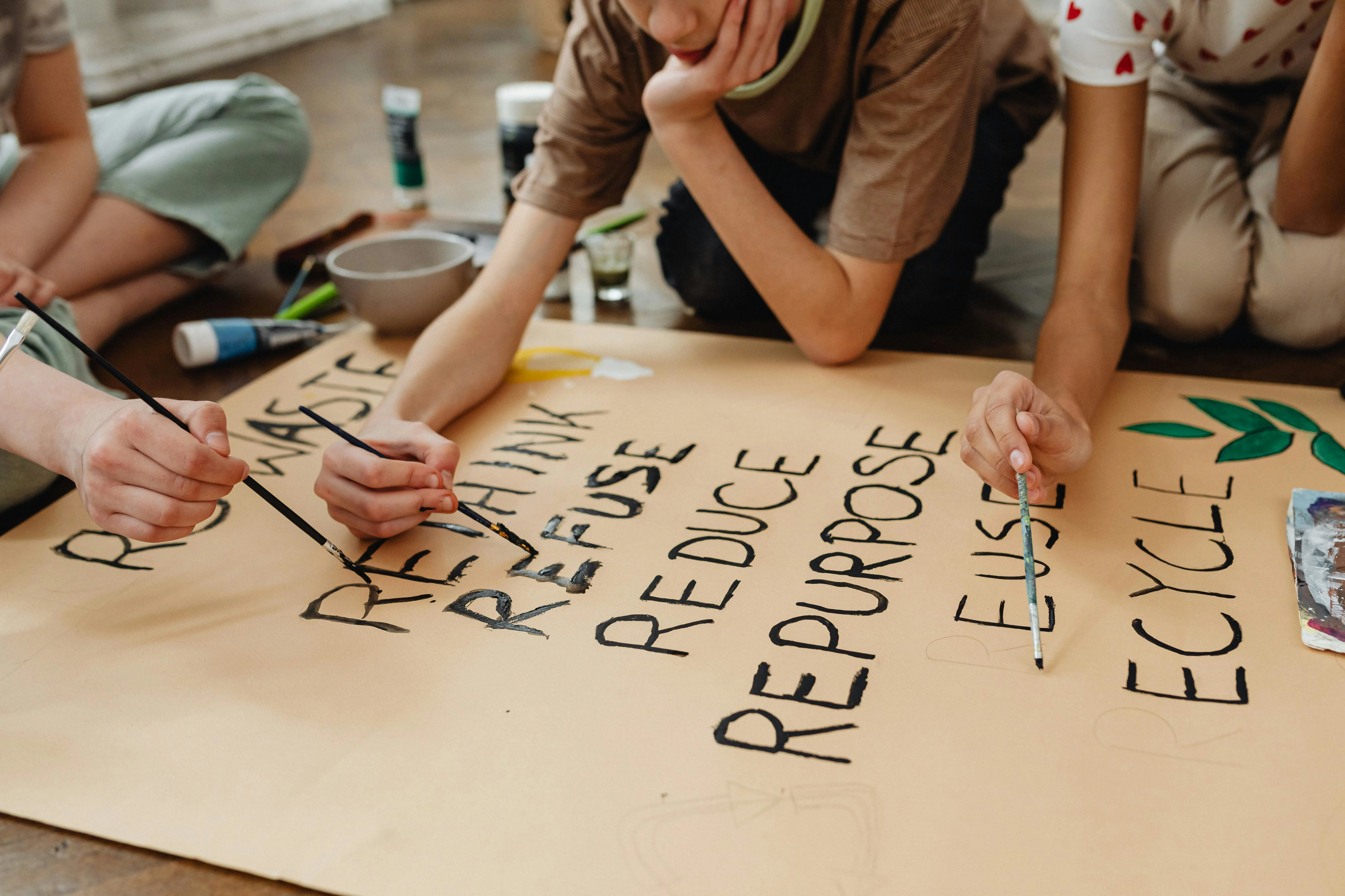 school children writing recycling terms with paint